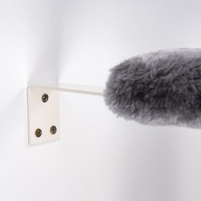Grey fur attachment cleans a white wall mount with four screws. Demonstration of the product’s cleaning function.