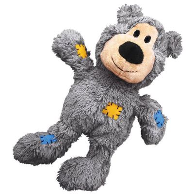 Juguete de peluche marrón en forma de oso con detalles bordados, incluye un parche azul y uno de cuadros en las patas.