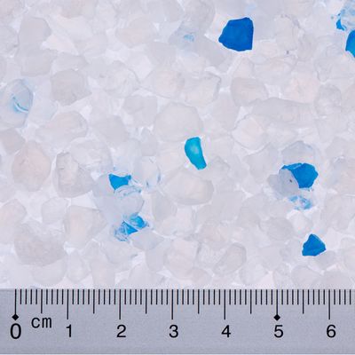 Close-up of white and blue silica litter crystals with a centimetre scale for size determination.