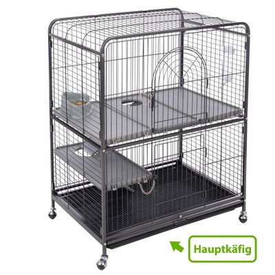 Fém ketrec két szinttel, rámpákkal és etetőrésszel. „Hauptkäfig” felirat zöld nyíllal.