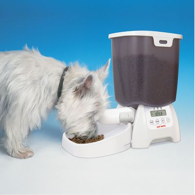 Automatyczny podajnik karmy Cat Mate z wyświetlaczem cyfrowym, napełniony suchą karmą. Pies je z miski.