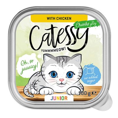 Catessy Junior macskaeledel csirkével, darabok szószban, hozzáadott cukor nélkül, 100g. Illusztráció szürke macskáról kék háttérrel, 'Oh, so juicy!' és 'Yummmmeow!' felirattal.