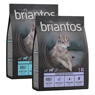 Dos sacos de pienso Briantos Adult, 1 kg. Etiquetas visibles: Adult, Salmon & Potato, Duck & Potato, Grain-Free Recipe, Semi-Moist Kibble, Made in Germany. Imagen de lobo en el envase.