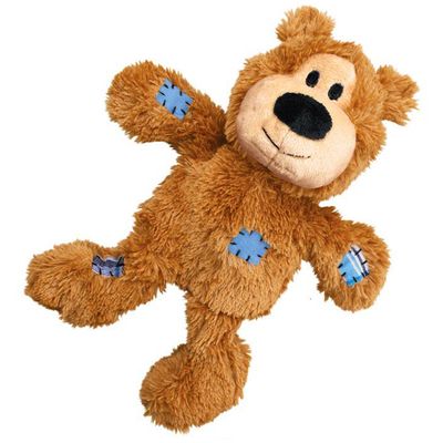 Juguete de peluche marrón en forma de oso con detalles bordados, incluye un parche azul y uno de cuadros en las patas.