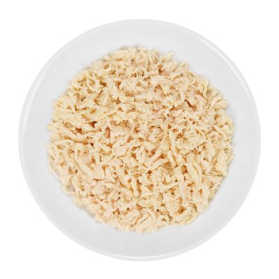 Primer plano de carne de pollo desmenuzada en un plato blanco, adecuado para mostrar el contenido o la consistencia del producto.