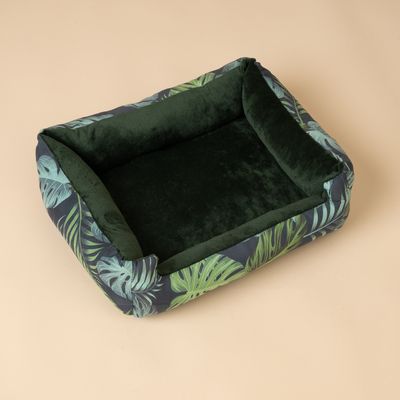 Cama rectangular para mascotas con funda de terciopelo verde oscuro y diseño de hojas tropicales en los laterales.