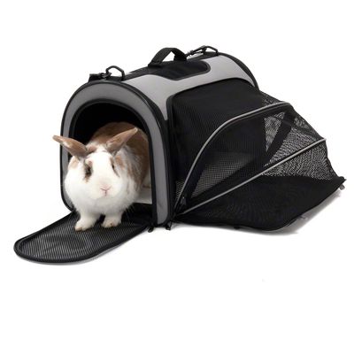 Bolsa de transporte con ventanas de malla y lateral extensible, apta para mascotas. Parte frontal abierta, animal saliendo.