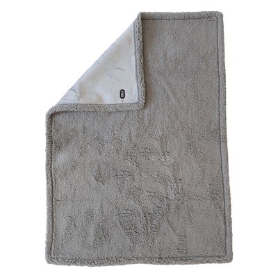 Graue, weiche Decke mit Plüschoberfläche und umgeschlagenem Rand. Kleine schwarze Marke sichtbar unten rechts.