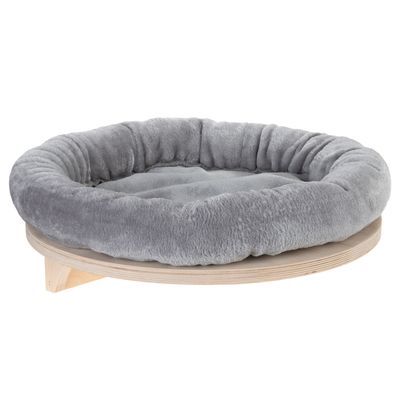 Wooden cat bed with beige padded edge, mounted on the wall. Grey cat sitting in the bed.