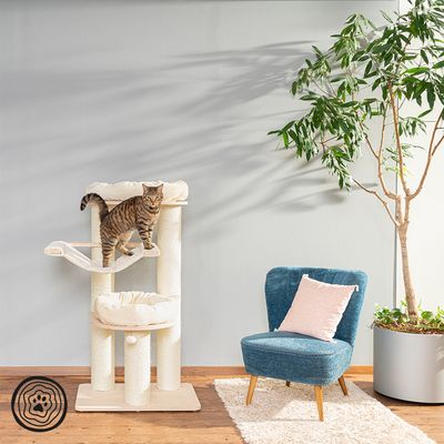 Cat tree with three levels, hammock and padded lying surfaces. Striped cat stands on the middle level. Logo visible bottom left.