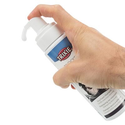 Trixie suhi šampon u pjeni, ruka pritišće pumpicu. Tekst: Nježno čišćenje bez vode, Dry Foam Shampoo.