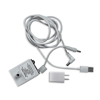 Bomba Pioneer Pet con cable USB, adaptador de corriente y conectores visibles. Texto en la bomba: 'Pioneer Pet Co., Ltd. Model: P-001 Input: DC 5V/1A'.