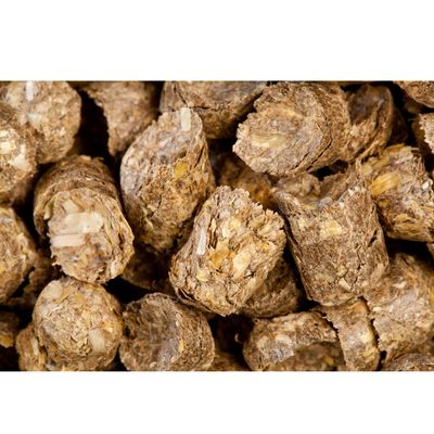 Close-up of compressed brown food pellets with visible flakes, showing texture and composition for product identification.