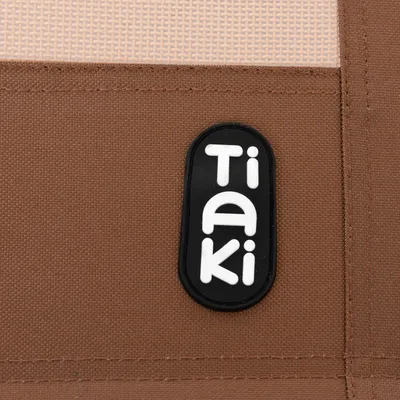 Tiaki-Logo auf braunem Stoffhintergrund. Tiaki-Logo auf braunem Stoffhintergrund.