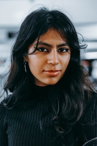 A woman with long black hair wearing a black turtle neck sweater.