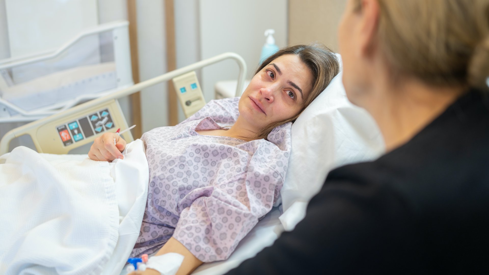 Szomorúan néz az anyjára egy kórházi ágyon fekvő nő
