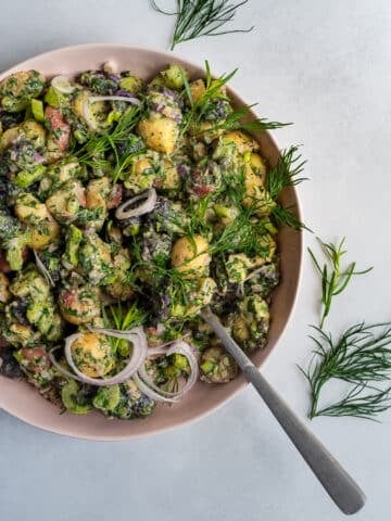 Herbed Potato Salad in a pink bowl garnished with dill and tarragon