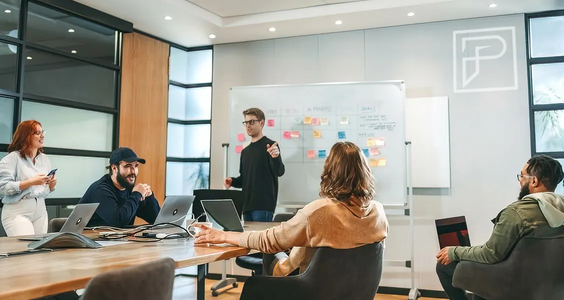 Team collaboration in a modern office, brainstorming ideas with a whiteboard and laptops, representing Piccola Tech's innovative and strategic approach.