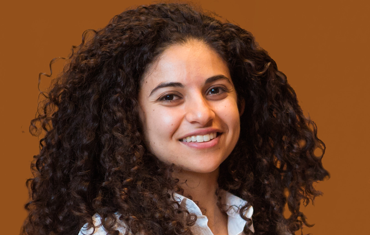 Woman smiles in front of a brown background