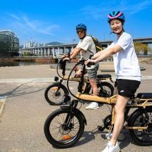 divi vīrieši ķiverēs stāv blakus velosipēdam