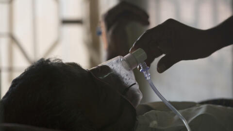 A relative adjusts the oxygen mask of a patient at a hospital in Hyderabad, India, on 24 March 2018.