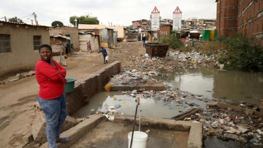 Une femme va chercher de l'eau à la borne dans le township d'Alexandra à Johannesburg en Afrique du Sud.