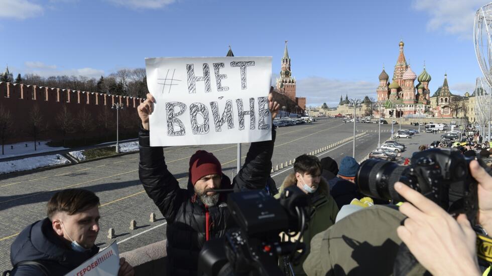 Чоловік тримає плакат із написом «Ні війни», поки люди кладуть квіти біля місця розстрілу лідера російської опозиції Бориса Нємцова, 27 лютого 2024