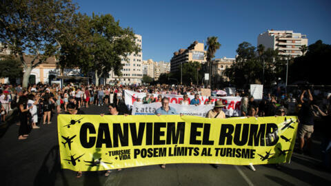 Varias personas participan en una protesta contra el turismo de masas en Palma de Mallorca, España, el 21 de julio de 2024. En la pancarta se lee "Cambiemos de rumbo, pongamos límites al turismo". REUTERS/Stringer