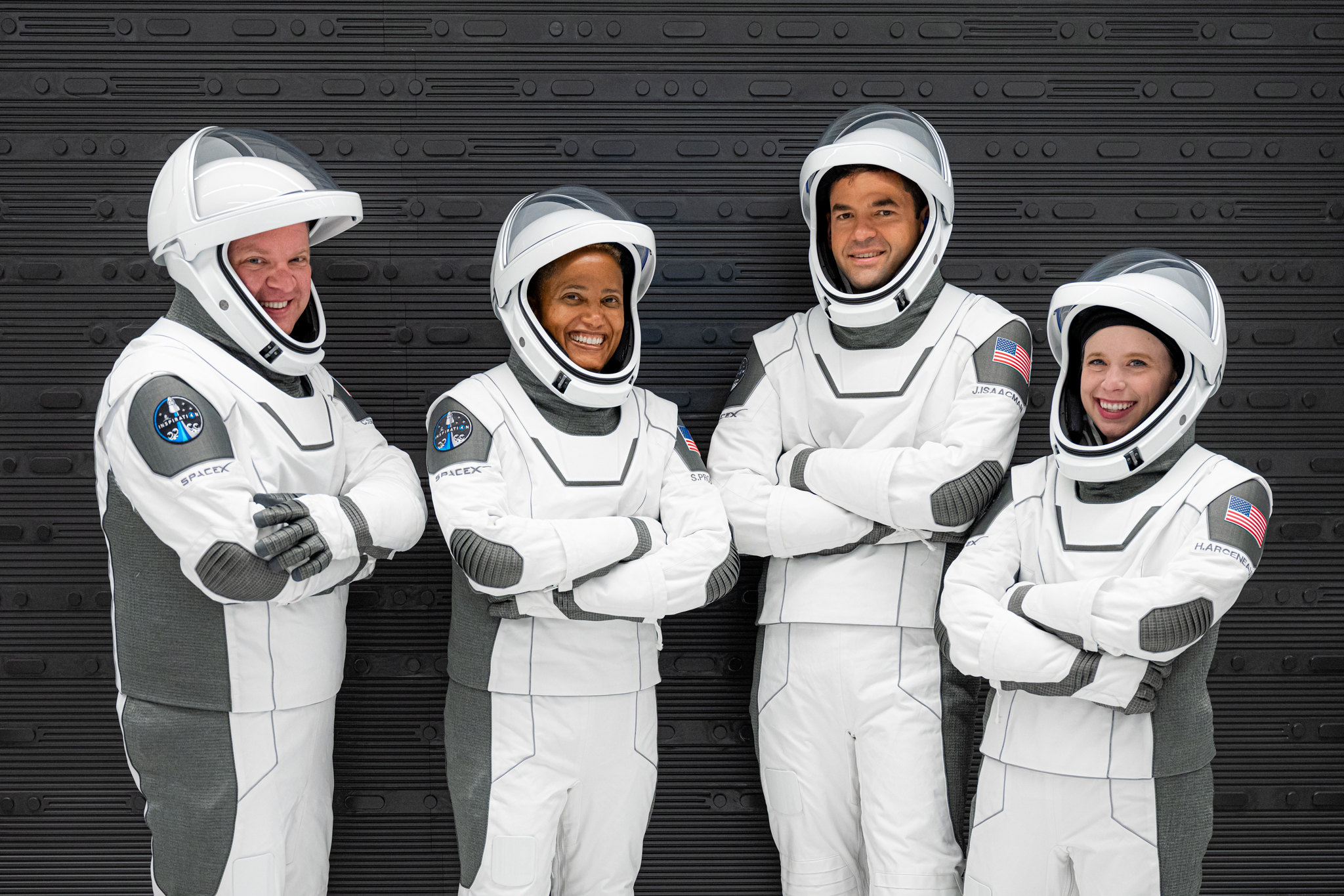 NASA Open Science. Four astronauts in white suits are smiling at the camera. They are standing in front of a dark background