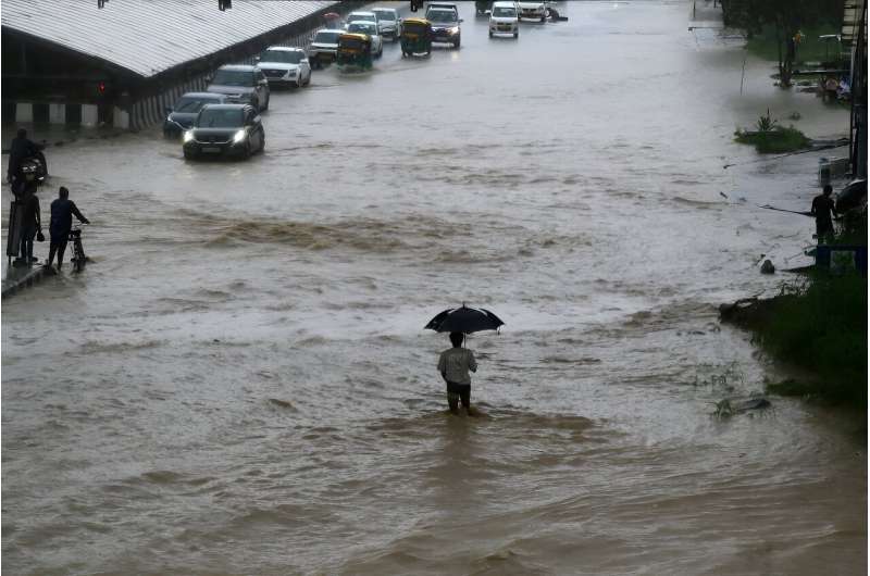 People commute through a waterlogged road after heavy rainfall in Gurgaon, outside India's capital New Delhi