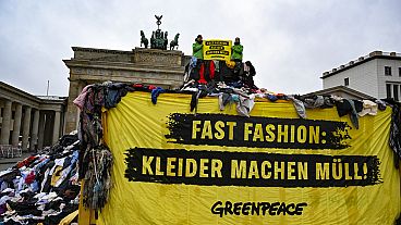 "Fast fashion: i vestiti fanno spazzatura!" è scritto su uno striscione esposto dagli attivisti di Greenpeace davanti alla Porta di Brandeburgo, a Berlino.