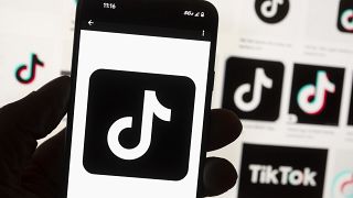 The TikTok logo is displayed n a mobile phone in front of a computer screen displaying the TikTok home screen, Oct. 14, 2022, in Boston