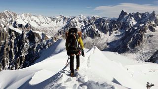 Un alpinista scende da una cresta dell'Aiguille du Midi verso la Vallee Blanche sul massiccio del Monte Bianco, nelle Alpi, vicino a Chamonix, in Francia.