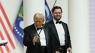 Il Presidente Donald Trump, a sinistra, impugna una sciabola dopo averla usata per tagliare una torta al Commander's Ball, parte della 60esima inaugurazione presidenziale.