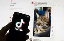 The TikTok logo is seen on a mobile phone in front of a computer screen which displays the TikTok home screen, on March 18, 2023.