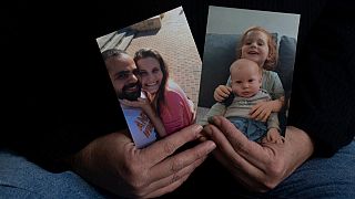 Yifat Zailer shows photos of her cousin, Shiri Bibas, center, her husband Yarden, left, and their children Ariel, top right, and Kfir, who are held hostage by Hamas.