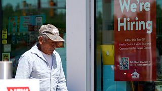 A hiring sign is displayed at a gas station as a customer walks past in Buffalo Grove, Ill., Thursday, June 9, 2022. 