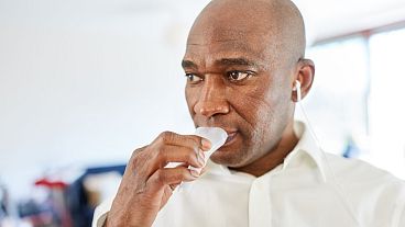 Um homem dá uma amostra de saliva para um teste em casa.