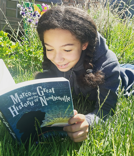 A middle school girl reading Marco the Great and the History of Numberville smiling