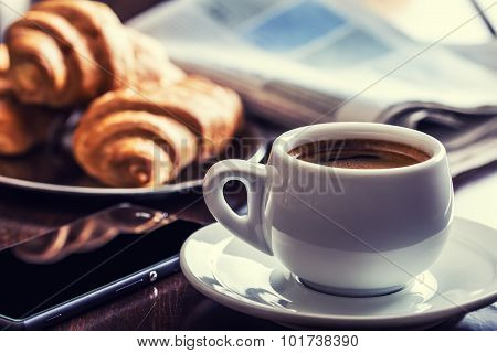 Coffee break business. Cup of coffee mobile phone croissants  and newspaper.