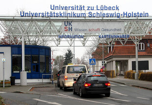 Autos warten vor der Einfahrt zum Lübecker Universitätsklinikum.