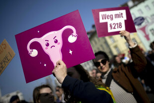 Demonstrierende halten Protestschilder mit der Aufschrift „Weg mit Paragraph § 218" in die Höhe