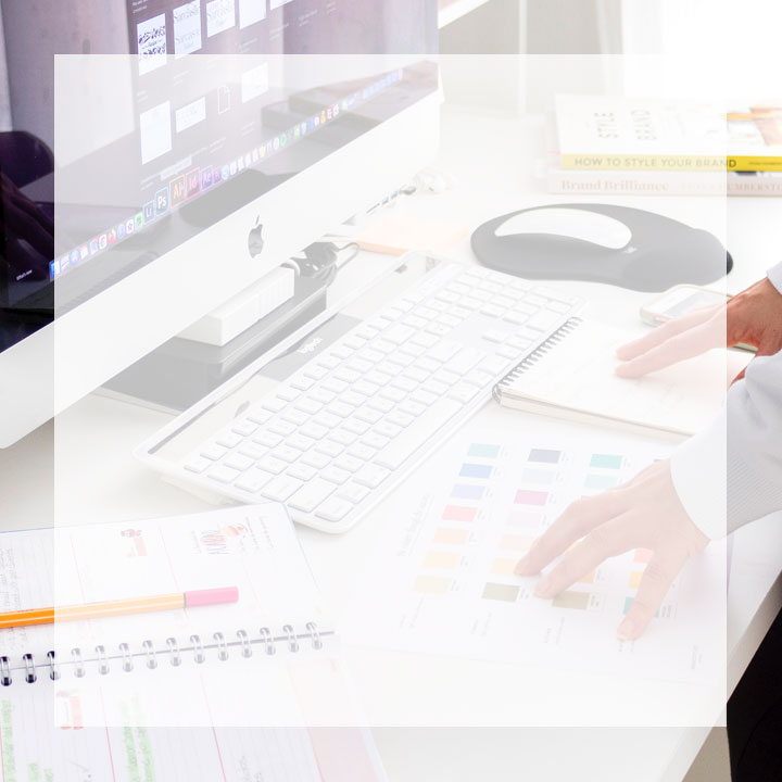 Hands on a table with color palettes, planners and computer