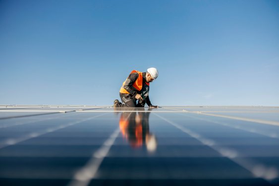 A handyman on the rooftop installing solar panels.