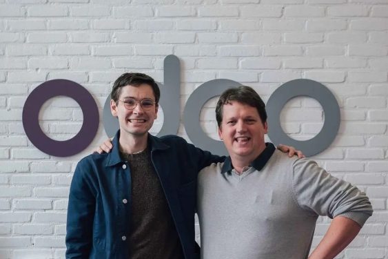 Odoo founders standing in front of Odoo logo