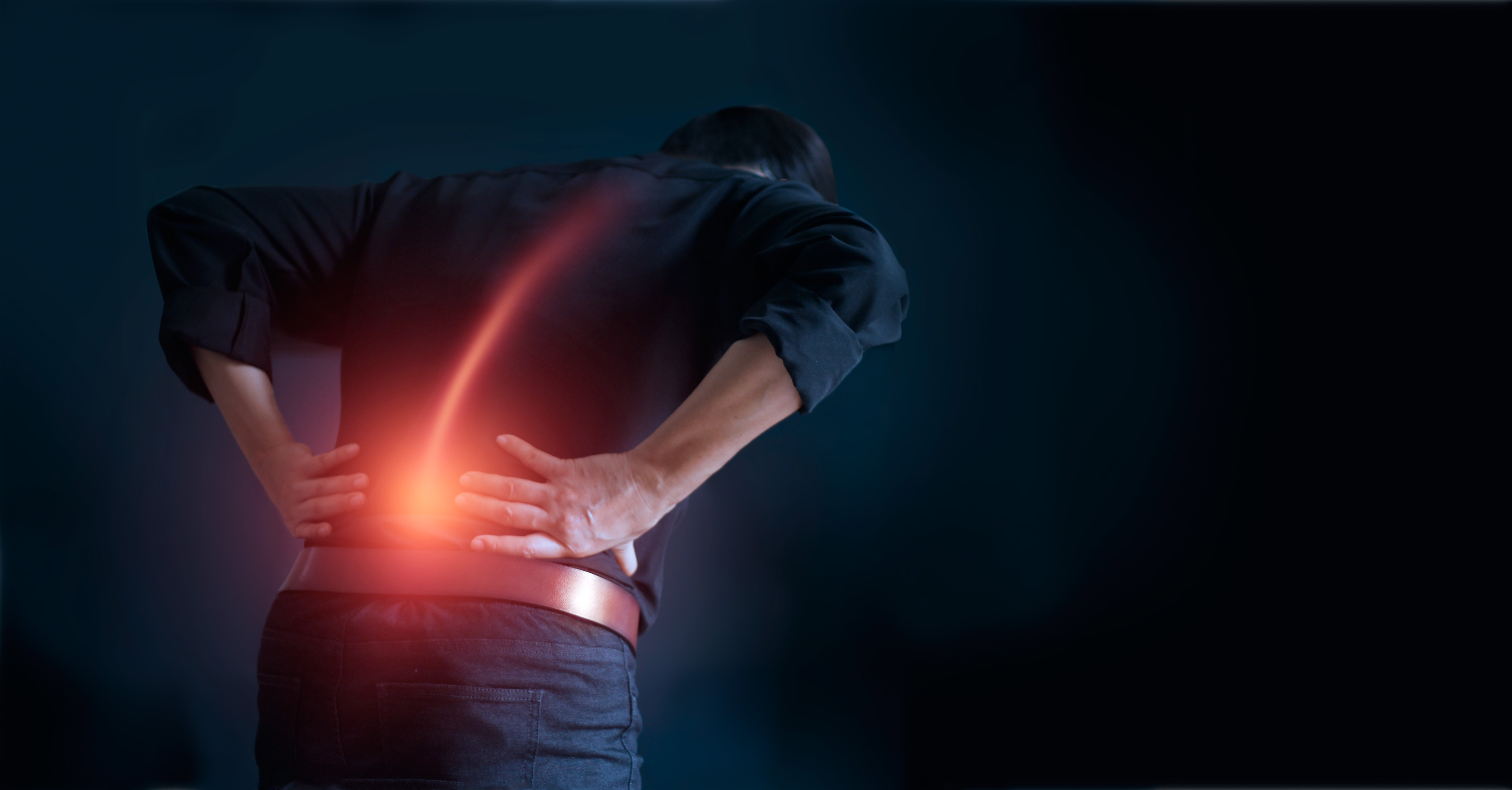Man suffering from back pain cause of office syndrome, his hands touching on lower back. Medical and heathcare concept.