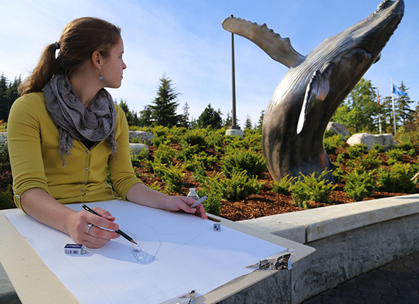 Student drawing a whale using a statue as a model
