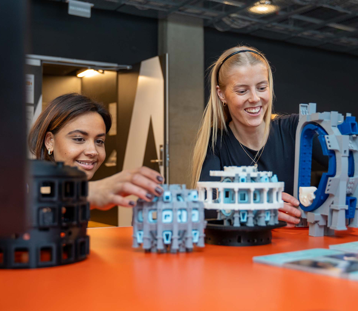 To studenter bygger avansert lego på en stand under åpen dag. Foto