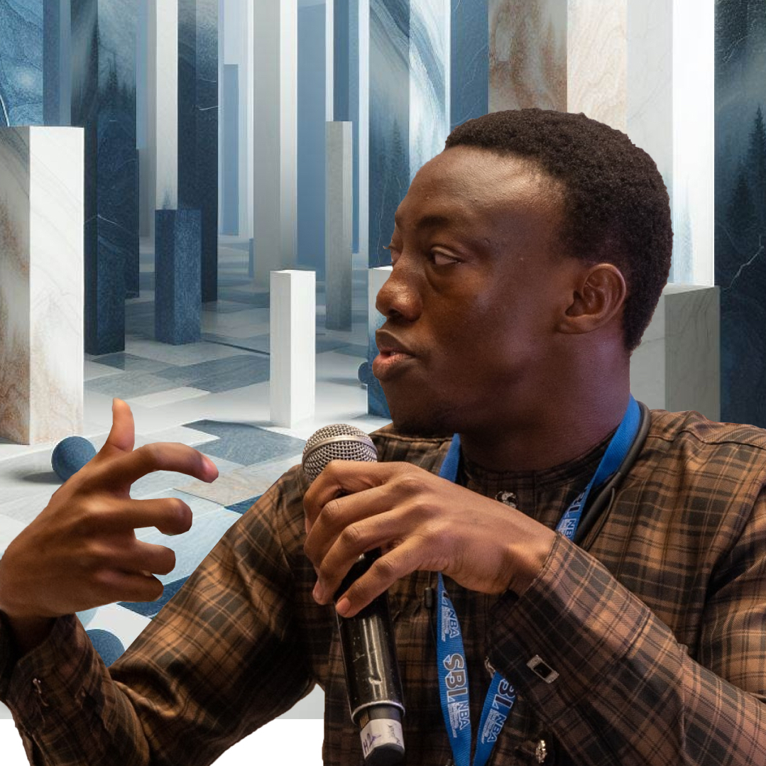 A man is speaking into a microphone in front of a white background.