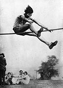 Photo en noir et blanc d'une femme élancée dans les airs et au-dessus de la barre de saut en hauteur.